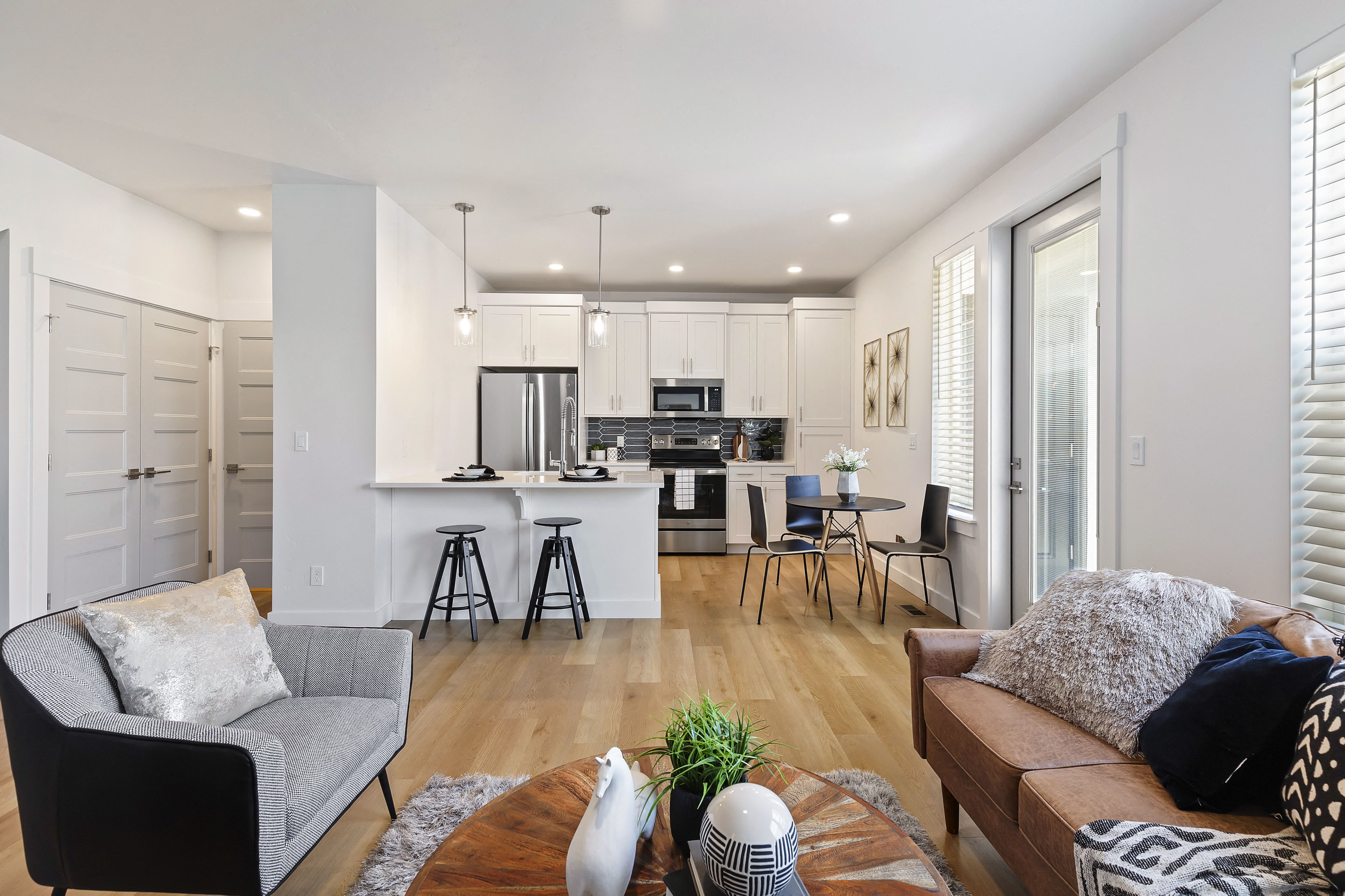 a living room and kitchen area with white walls and hardwood floors at Alante Homes at Lake Hazel, Boise, ID, 83709